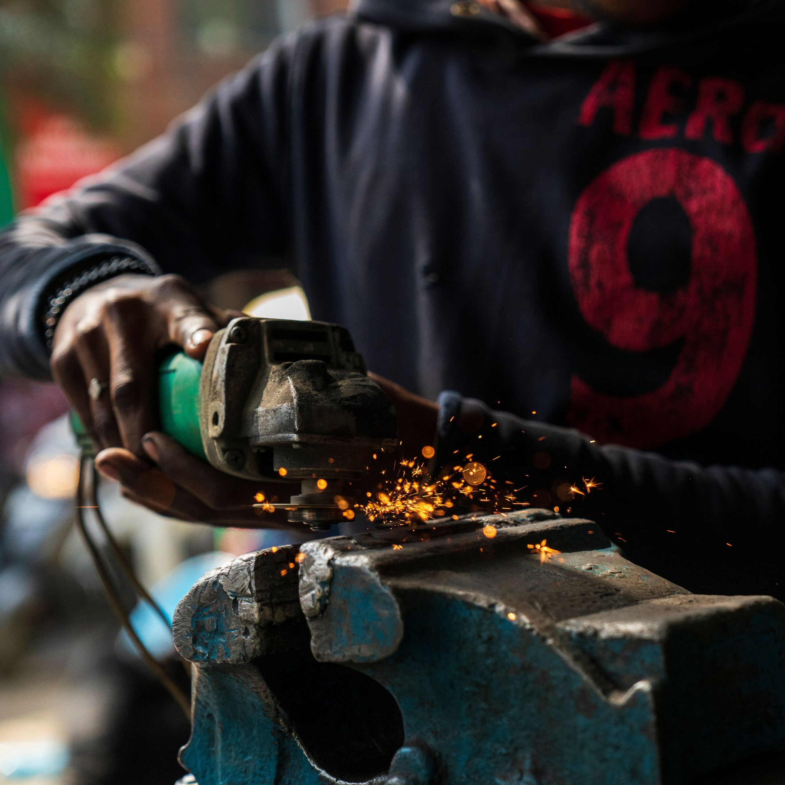 Factory production line worker welding metal details, professional manufacturing services for custom enamel pins and hardware
