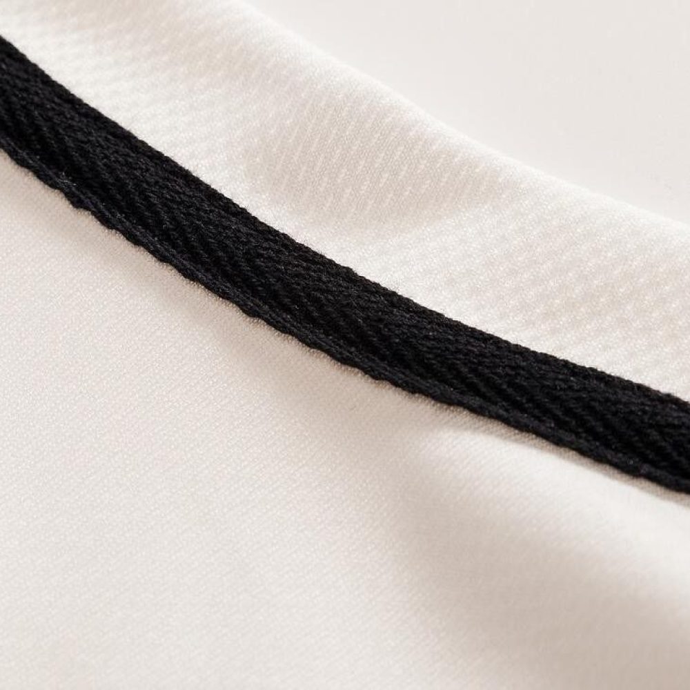 Custom jersey fabric edge stitching detail, black reinforced seam on white breathable athletic material for sportswear manufacturing